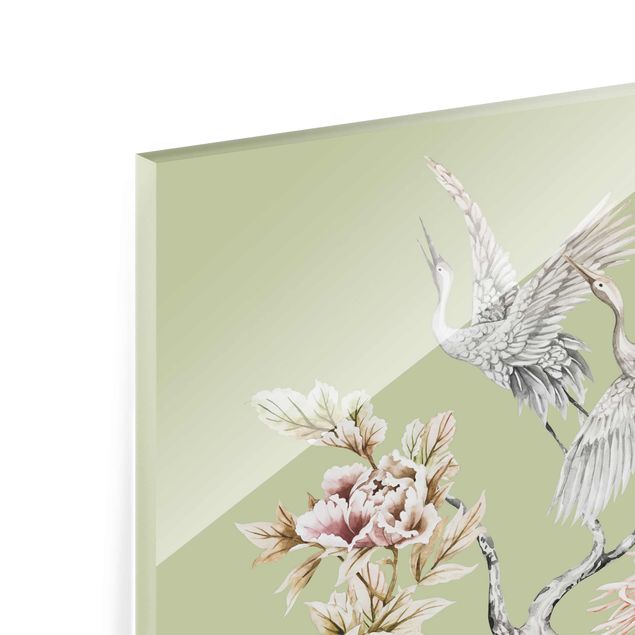 Quadro in vetro - Acquerello di cicogne in volo con fiori su verde