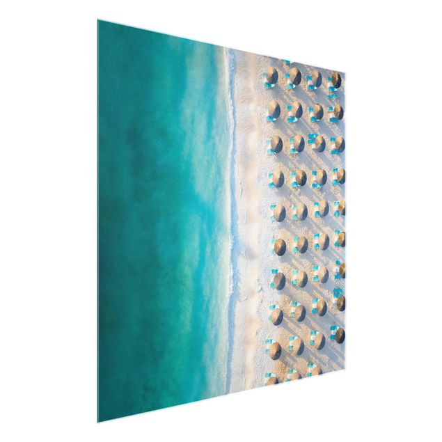 Quadro in vetro - Spiaggia sabbiosa bianca con ombrelloni di paglia