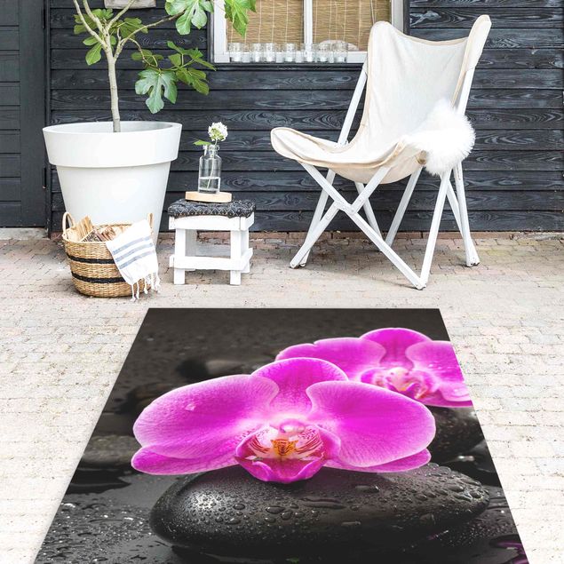 Tappeti moderni soggiorno Fiore di orchidea rosa su pietra con gocce